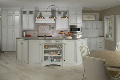 Open concept kitchen - large transitional l-shaped light wood floor and beige floor open concept kitchen idea in Orlando with recessed-panel cabinets, white cabinets, beige backsplash, stainless steel appliances and an island