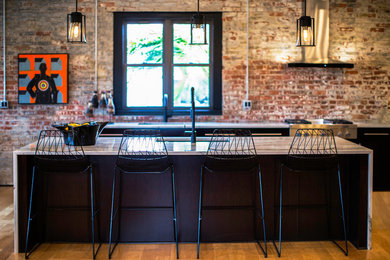 Open concept kitchen - large industrial l-shaped light wood floor and beige floor open concept kitchen idea in Other with an undermount sink, flat-panel cabinets, dark wood cabinets, marble countertops, red backsplash, brick backsplash, stainless steel appliances, an island and white countertops