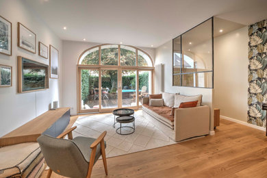 Idée de décoration pour un salon design de taille moyenne et ouvert avec un mur beige, parquet clair, aucune cheminée et un téléviseur dissimulé.