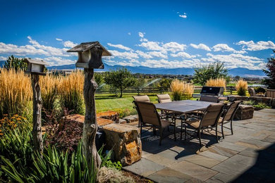 This is an example of a large country backyard full sun garden for fall in Other with a retaining wall and natural stone pavers.
