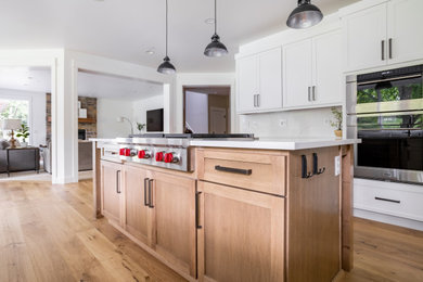 Example of a large transitional u-shaped medium tone wood floor and brown floor open concept kitchen design in Seattle with shaker cabinets, white cabinets, quartz countertops and an island