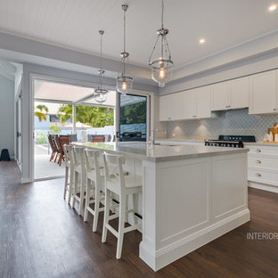 Large beach style kitchen pantry remodeling - Large coastal l-shaped vinyl floor kitchen pantry photo in Gold Coast - Tweed with an undermount sink, recessed-panel cabinets, white cabinets, quartz countertops, blue backsplash, porcelain backsplash, black appliances and an island