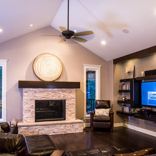 Mittelgroßes, Offenes Mediterranes Wohnzimmer mit beiger Wandfarbe, braunem Holzboden, Kamin, Kaminsims aus Stein und Wand-TV in Edmonton