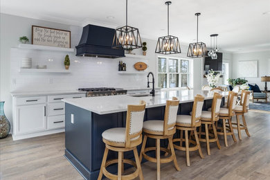 Large beach style l-shaped eat-in kitchen photo in DC Metro with an undermount sink, recessed-panel cabinets, white backsplash, subway tile backsplash, stainless steel appliances, an island and multicolored countertops