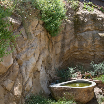 Custom fountain nestled into hillside with native plants and boulders
