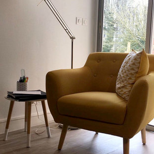 This is an example of a large modern home office and library in Bordeaux with a reading nook, white walls, laminate floors, a freestanding desk and beige floors.