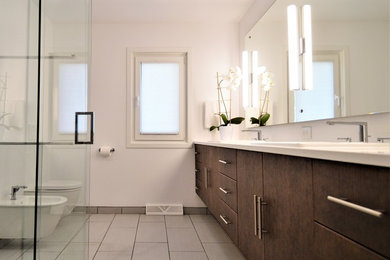 Exemple d'une grande salle de bain principale moderne avec un placard à porte plane, des portes de placard marrons, une douche d'angle, WC suspendus, un mur blanc, un sol en carrelage de porcelaine, un lavabo posé, un plan de toilette en surface solide, un sol gris, une cabine de douche à porte battante et un plan de toilette blanc.