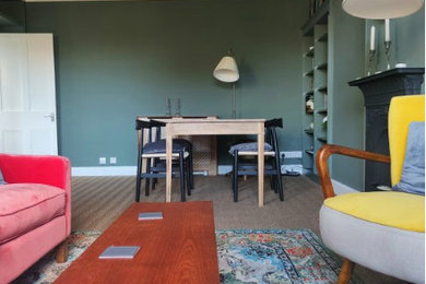 他の地域にある高級なトラディショナルスタイルのおしゃれなLDK (緑の壁、竹フローリング、標準型暖炉、金属の暖炉まわり、据え置き型テレビ、茶色い床、羽目板の壁) の写真