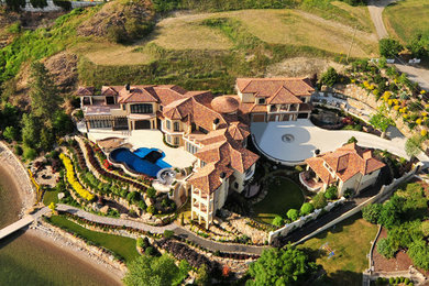 Huge tuscan beige three-story stone exterior home photo in Vancouver with a hip roof
