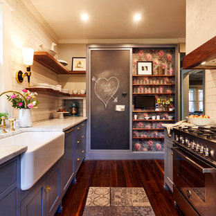 На фото: маленькая отдельная, параллельная кухня в классическом стиле с раковиной в стиле кантри, фасадами в стиле шейкер, синими фасадами, белым фартуком, фартуком из плитки кабанчик, техникой из нержавеющей стали и паркетным полом среднего тона без острова с