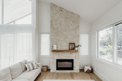 Inspiration for a beach style living room in Sydney with a stone fireplace surround.