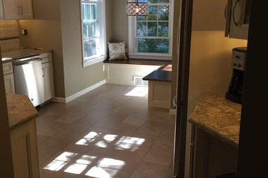 Inspiration for a mid-sized craftsman u-shaped eat-in kitchen remodel in New York with a double-bowl sink, white cabinets, white backsplash, stainless steel appliances and no island