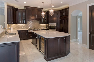 Mid-sized traditional l-shaped open plan kitchen in Sacramento with raised-panel cabinets, dark wood cabinets, marble benchtops, beige splashback, subway tile splashback, stainless steel appliances, marble floors and with island.