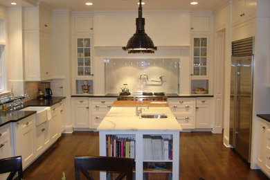Large u-shaped medium tone wood floor eat-in kitchen photo in Chicago with a farmhouse sink, recessed-panel cabinets, white cabinets, granite countertops, white backsplash, subway tile backsplash, stainless steel appliances and an island