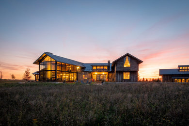 Diseño de fachada de casa marrón rural extra grande de dos plantas con revestimiento de piedra y tejado de metal