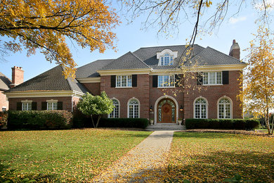 Large elegant brown two-story brick exterior home photo in Chicago with a hip roof