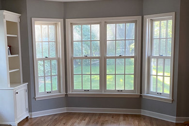 Example of a large arts and crafts light wood floor, beige floor and wainscoting kitchen/dining room combo design in Cedar Rapids with gray walls, a standard fireplace and a tile fireplace