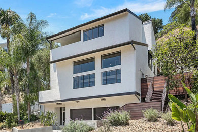Inspiration for a large contemporary beige four-story stucco and board and batten house exterior remodel in Los Angeles with a butterfly roof, a shingle roof and a brown roof