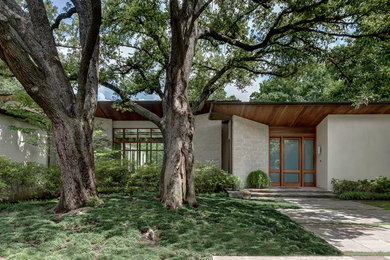 Example of a large trendy beige two-story stone exterior home design in Dallas with a mixed material roof