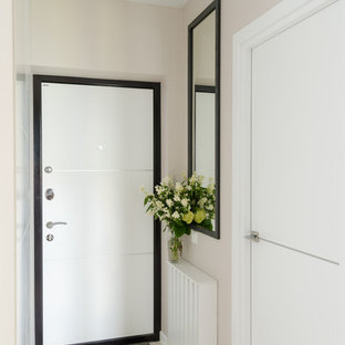 Ispirazione per una porta d'ingresso contemporanea di medie dimensioni con pavimento in laminato, pavimento bianco, pareti beige, una porta singola e una porta bianca