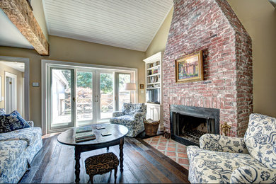 Living room - small rustic loft-style dark wood floor and brown floor living room idea in Toronto with yellow walls, a standard fireplace and a brick fireplace