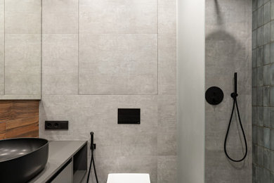 Modelo de cuarto de baño principal y único contemporáneo pequeño con puertas de armario grises, ducha abierta, sanitario de pared, baldosas y/o azulejos grises, baldosas y/o azulejos de porcelana, paredes grises, suelo de baldosas de porcelana, lavabo encastrado y ducha abierta