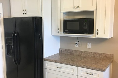 This is an example of a mid-sized transitional l-shaped eat-in kitchen in Orlando with a double-bowl sink, shaker cabinets, white cabinets, laminate benchtops, multi-coloured splashback, black appliances, ceramic floors, with island and beige floor.