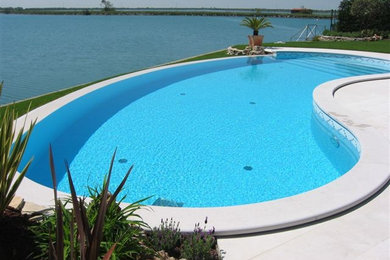 Esempio di una piscina a sfioro infinito tradizionale rotonda di medie dimensioni e dietro casa con piastrelle