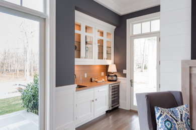 Transitional medium tone wood floor home bar photo in New York with an undermount sink, white cabinets, wood countertops and wood backsplash