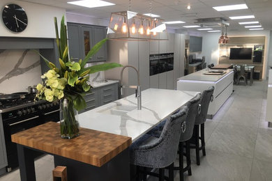 Design ideas for a mid-sized galley eat-in kitchen in Oxfordshire with a drop-in sink, quartzite benchtops, black appliances and grey floor.