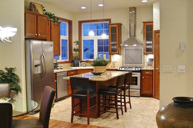 Inspiration for a mid-sized timeless l-shaped travertine floor enclosed kitchen remodel in Other with a drop-in sink, beaded inset cabinets, medium tone wood cabinets, granite countertops, beige backsplash, porcelain backsplash, stainless steel appliances and an island