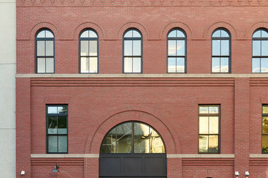 Example of a large transitional red three-story brick townhouse exterior design in New York with a metal roof