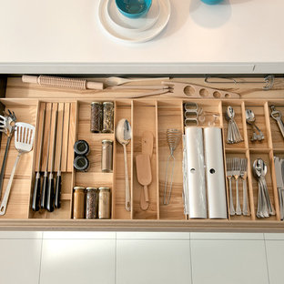 Foto di una piccola cucina a L contemporanea con paraspruzzi bianco, paraspruzzi con lastra di vetro, pavimento con piastrelle in ceramica, ante in legno chiaro e elettrodomestici in acciaio inossidabile