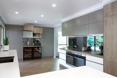 Design ideas for a large contemporary l-shaped eat-in kitchen in Brisbane with an undermount sink, flat-panel cabinets, white cabinets, quartz benchtops, metallic splashback, mosaic tile splashback, stainless steel appliances, porcelain floors, a peninsula, brown floor and white benchtop.