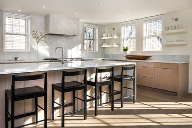This is an example of a mid-sized contemporary l-shaped eat-in kitchen in Boston with a single-bowl sink, flat-panel cabinets, light wood cabinets, marble benchtops, white splashback, marble splashback, panelled appliances, light hardwood floors, with island and white benchtop.