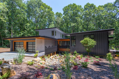 Large and multi-coloured contemporary two floor detached house in Raleigh with metal cladding, a lean-to roof, a mixed material roof and a black roof.