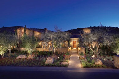 Example of a large tuscan beige two-story stone exterior home design in Orange County with a tile roof