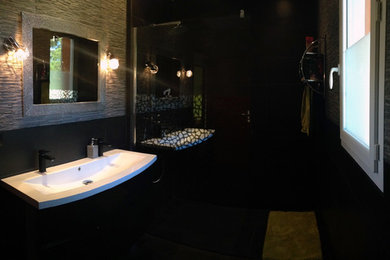 Cette photo montre une salle de bain principale tendance de taille moyenne avec un placard sans porte, des portes de placard noires, une douche à l'italienne, un carrelage noir, des carreaux en terre cuite, un mur noir, tomettes au sol, un lavabo suspendu, un plan de toilette en surface solide, un sol noir et aucune cabine.