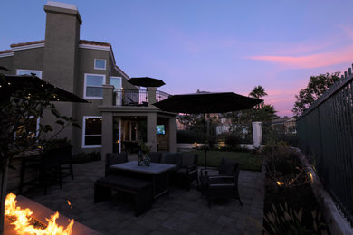 Inspiration for a mid-sized timeless backyard concrete paver patio remodel in Orange County with a fireplace and a roof extension