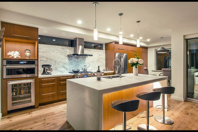 Example of a trendy galley light wood floor and brown floor kitchen design in San Diego with a single-bowl sink, flat-panel cabinets, marble countertops, white backsplash, marble backsplash, stainless steel appliances, an island and white countertops