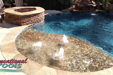 Modelo de piscina con fuente natural mediterránea grande a medida en patio trasero con losas de hormigón
