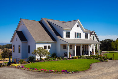Example of a large country white three-story house exterior design in Portland
