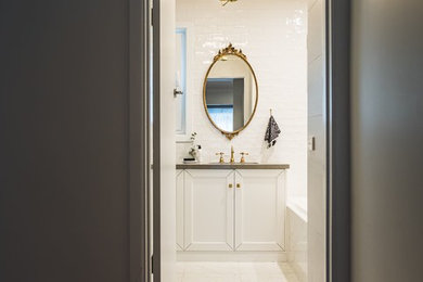 Mid-sized traditional master bathroom in Melbourne with shaker cabinets, white cabinets, a drop-in tub, a corner shower, a wall-mount toilet, gray tile, porcelain tile, grey walls, porcelain floors, an undermount sink, engineered quartz benchtops, white floor, a hinged shower door and grey benchtops.