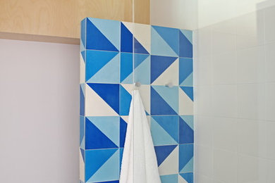 This is an example of a mid-sized modern master bathroom in Barcelona with flat-panel cabinets, white cabinets, a curbless shower, a wall-mount toilet, multi-coloured tile, ceramic tile, white walls, ceramic floors, an undermount sink, wood benchtops, multi-coloured floor and a hinged shower door.