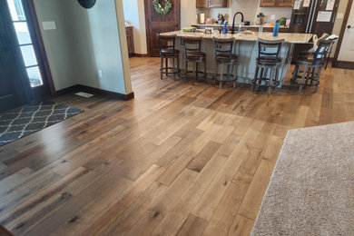 Example of a mid-sized mountain style medium tone wood floor, multicolored floor, vaulted ceiling and wall paneling front door design in Other with a dark wood front door and white walls