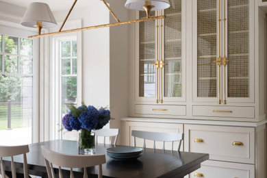 Example of a mid-sized classic u-shaped medium tone wood floor and brown floor enclosed kitchen design in DC Metro with a farmhouse sink, beaded inset cabinets, beige cabinets, quartz countertops, white backsplash, ceramic backsplash, stainless steel appliances, an island and white countertops