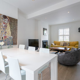 Offenes, Kleines Modernes Esszimmer mit weißer Wandfarbe, hellem Holzboden, Kaminsims aus Metall und braunem Boden in London