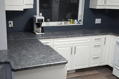 Kitchen - transitional medium tone wood floor and brown floor kitchen idea in Other with a drop-in sink, raised-panel cabinets, white cabinets, white appliances and laminate countertops