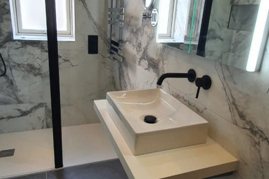 Mid-sized minimalist master black and white tile and marble tile porcelain tile, black floor and single-sink bathroom photo in Dublin with flat-panel cabinets, white cabinets, a wall-mount toilet, multicolored walls, a vessel sink, laminate countertops, white countertops and a floating vanity