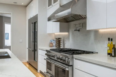 Eat-in kitchen - large contemporary single-wall brown floor eat-in kitchen idea in San Francisco with an undermount sink, flat-panel cabinets, white cabinets, quartzite countertops, gray backsplash, porcelain backsplash, stainless steel appliances, an island and beige countertops